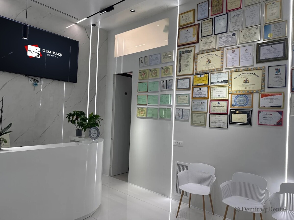 The reception of DemiraqiDental with the clinic logo on the TV and a wall of diplomas and certificates